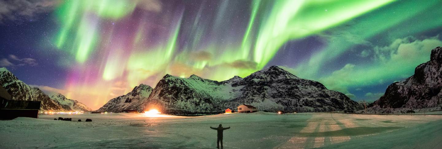 Aurora borealis (northern lights) over mountain with one person
