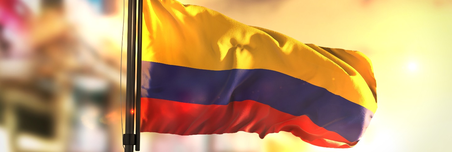 Colombia flag against city blurred background at sunrise backlight
