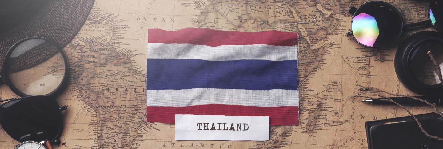 Thailand flag between traveler's accessories on old vintage map
