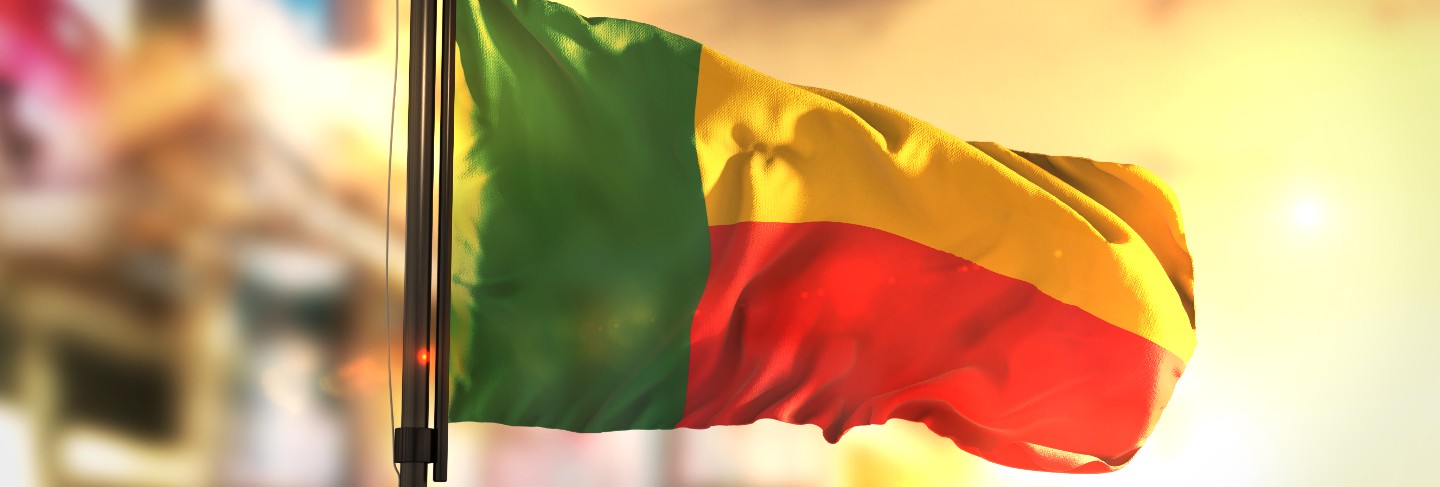 Benin flag against city blurred background at sunrise
