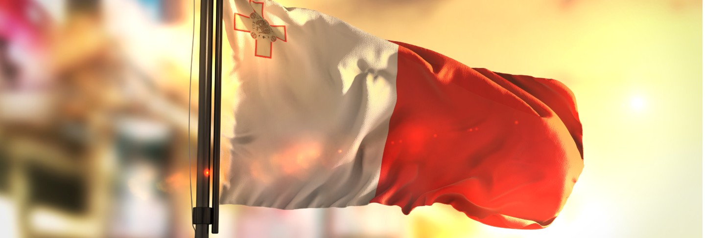 Malta flag against city blurred background at sunrise backlight