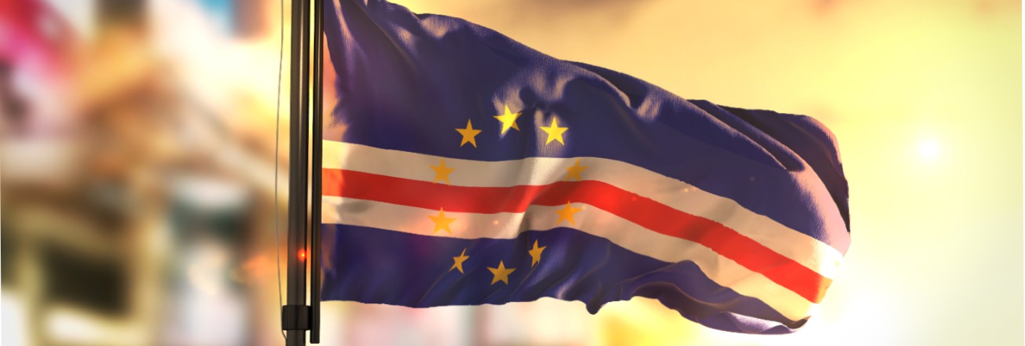 Cape verde flag against city blurred background at sunrise backlight
