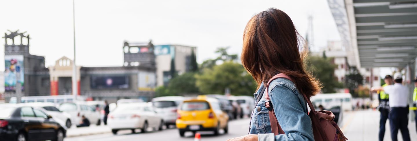 Young woman traveler with luggage looking for taxi at the airport
