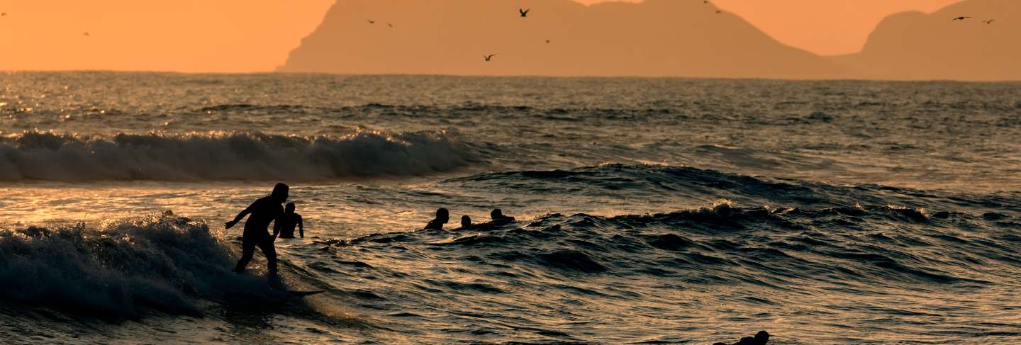 Pacific ocean. silhouettes of the surfers and the mountain at sunset time. lima, peru. south america 
