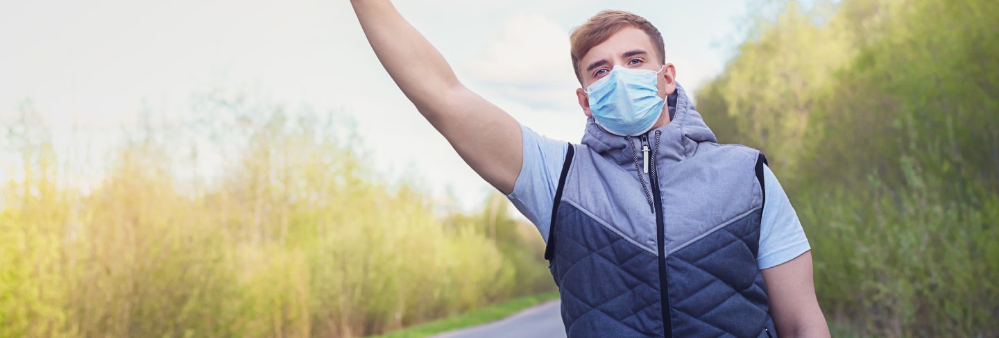 Guy in medical mask for prevention of coronavirus trying to stop auto, car.
