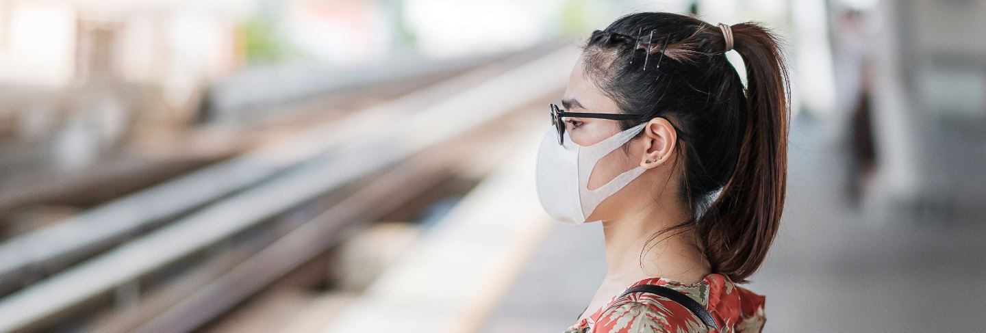 Young asian woman wearing surgical face mask protect coronavirus inflection at public train station
