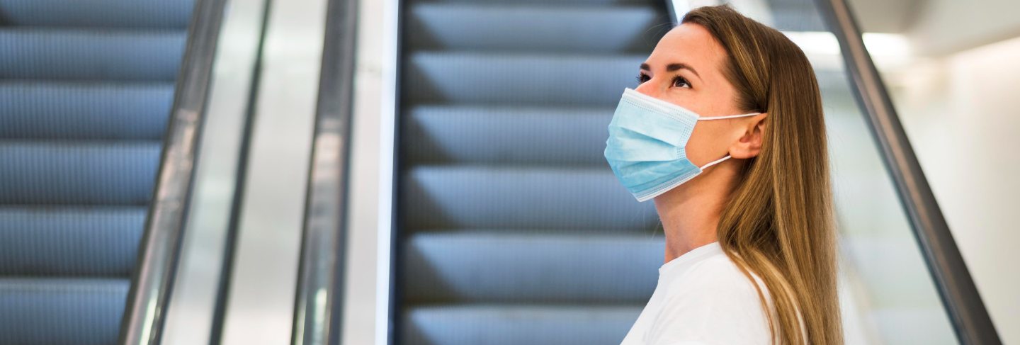 Woman with face mask on the escalator
