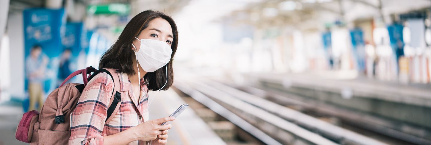 Asian woman wearing surgical face mask against novel coronavirus or coronavirus disease at public train station
