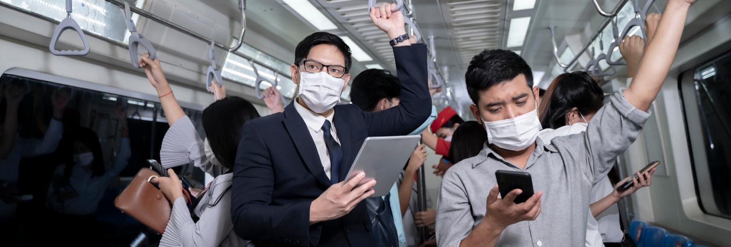 Business people standing in metro mass transit subway. man using tablet and smartphone. people wearing face mask. coronavirus flu virus in public travel. 
