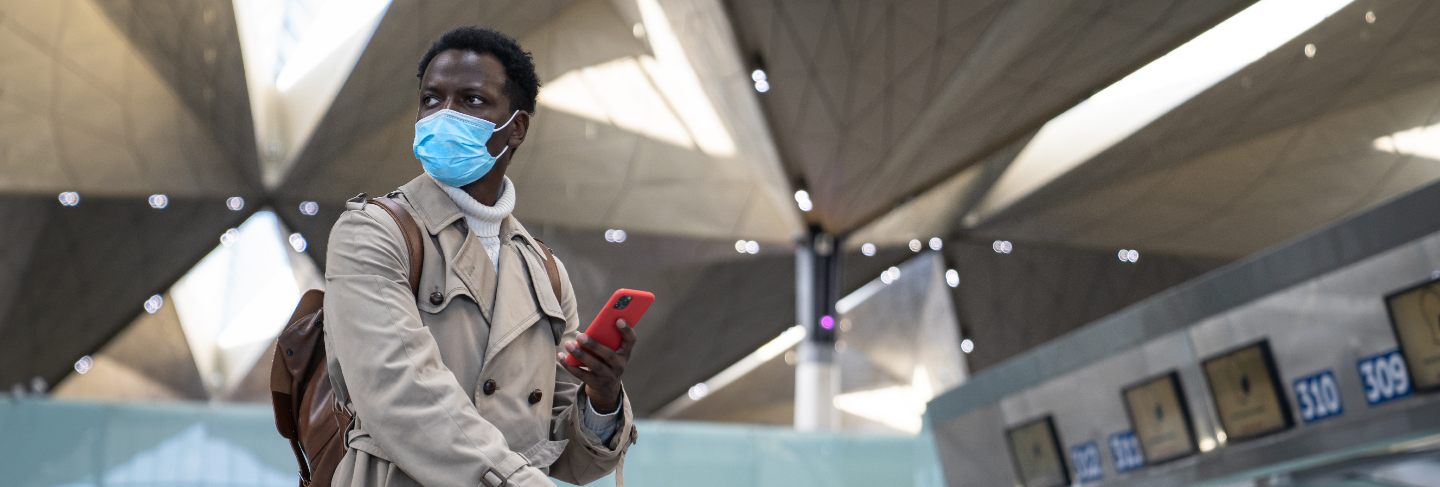 Black man standing at airport wearing face protective mask during virus epidemic, covid-19 
