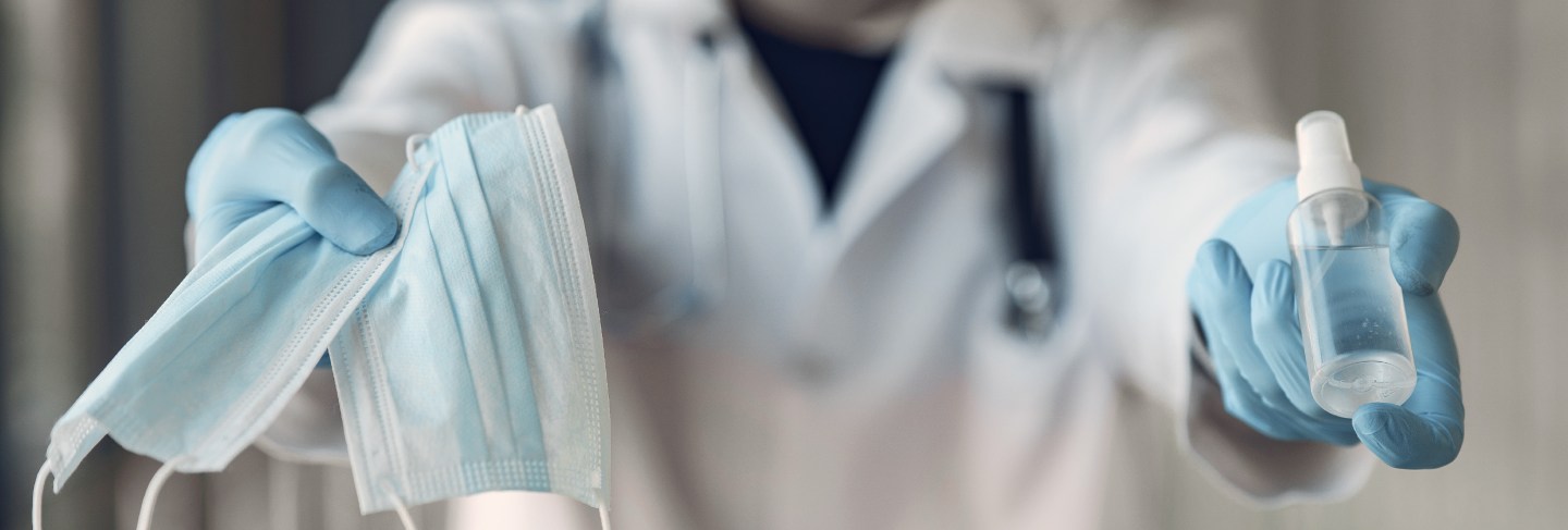 Doctor hold the antiseptic and masks in his hand
