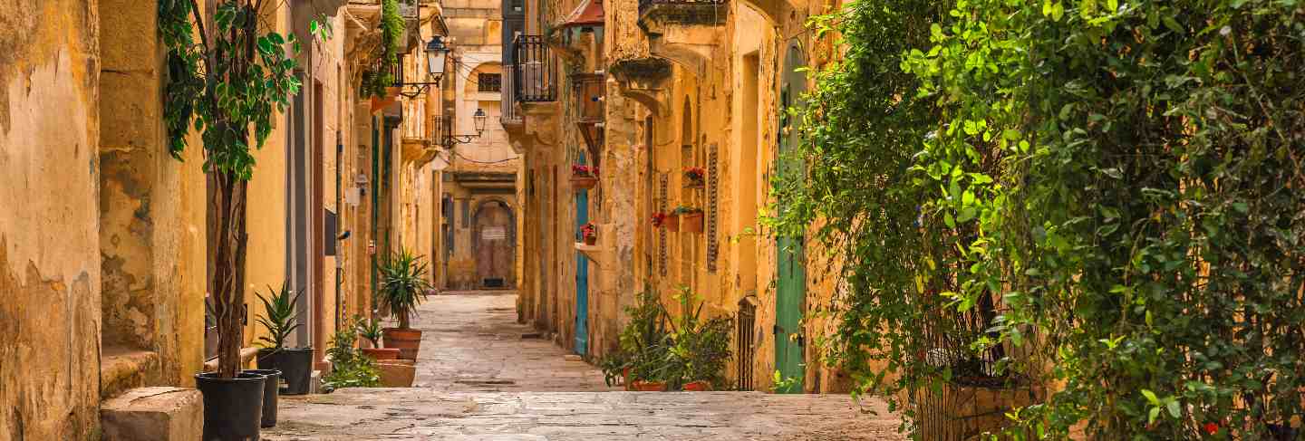 Valletta, malta. old medieval empty street with yellow buildings and flower pots Premium Photo